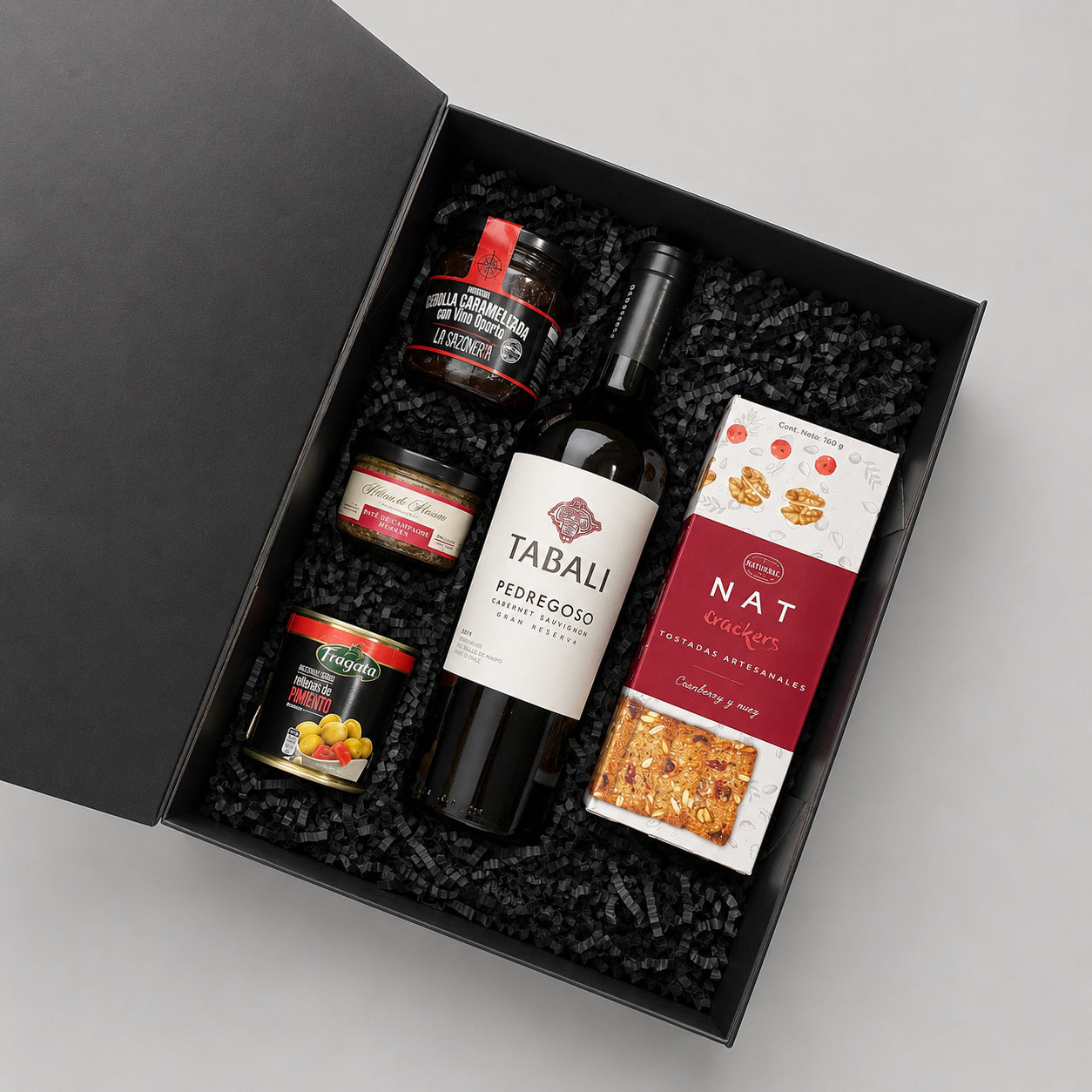 Caja gourmet con vino Tabalí Pedregoso, confitura artesanal, aceitunas rellenas, mousse o paté gourmet y crackers artesanales. Un regalo corporativo elegante para celebrar cualquier ocasión.
