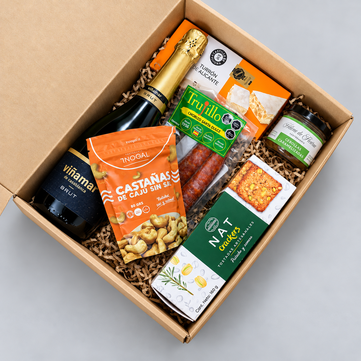 Caja gourmet con espumante Viña Mar Brut, turrón de Alicante, chorizo sarta, castañas de cajú y Nat Crackers. Incluye tarjeta con logo corporativo.