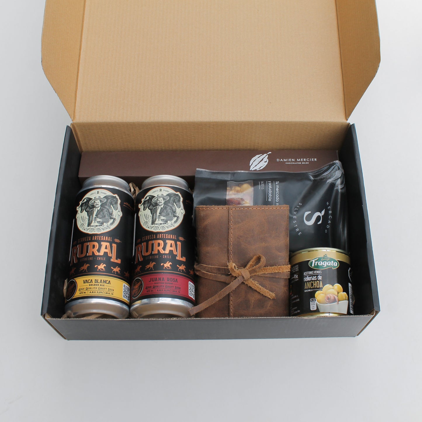 Diversión y placer en un solo kit. Incluye juego de naipes en estuche de cuero artesanal, 2 cervezas Rural, mix de frutos secos y bombones Damien Mercier. El regalo corporativo ideal para desconectar y compartir en el Día del Trabajador. ¡Personalízalo con tu logo!
