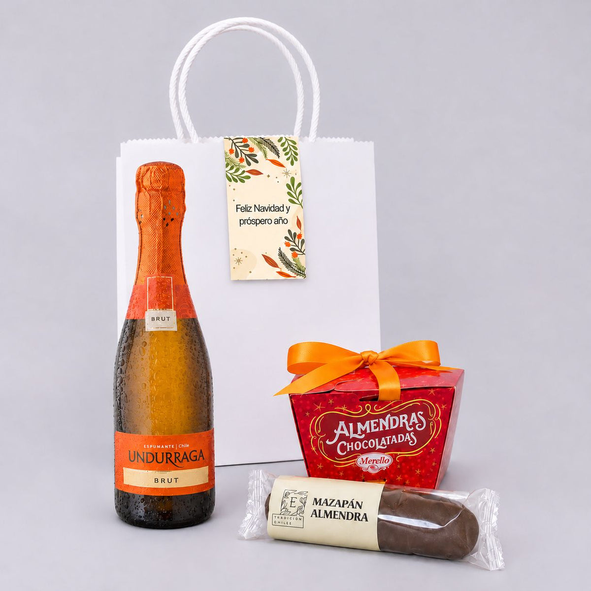 Regalo corporativo con espumante Undurraga Brut, almendras chocolatadas Merello y mazapán Entre Lagos. En bolsa con saludo corporativo. 