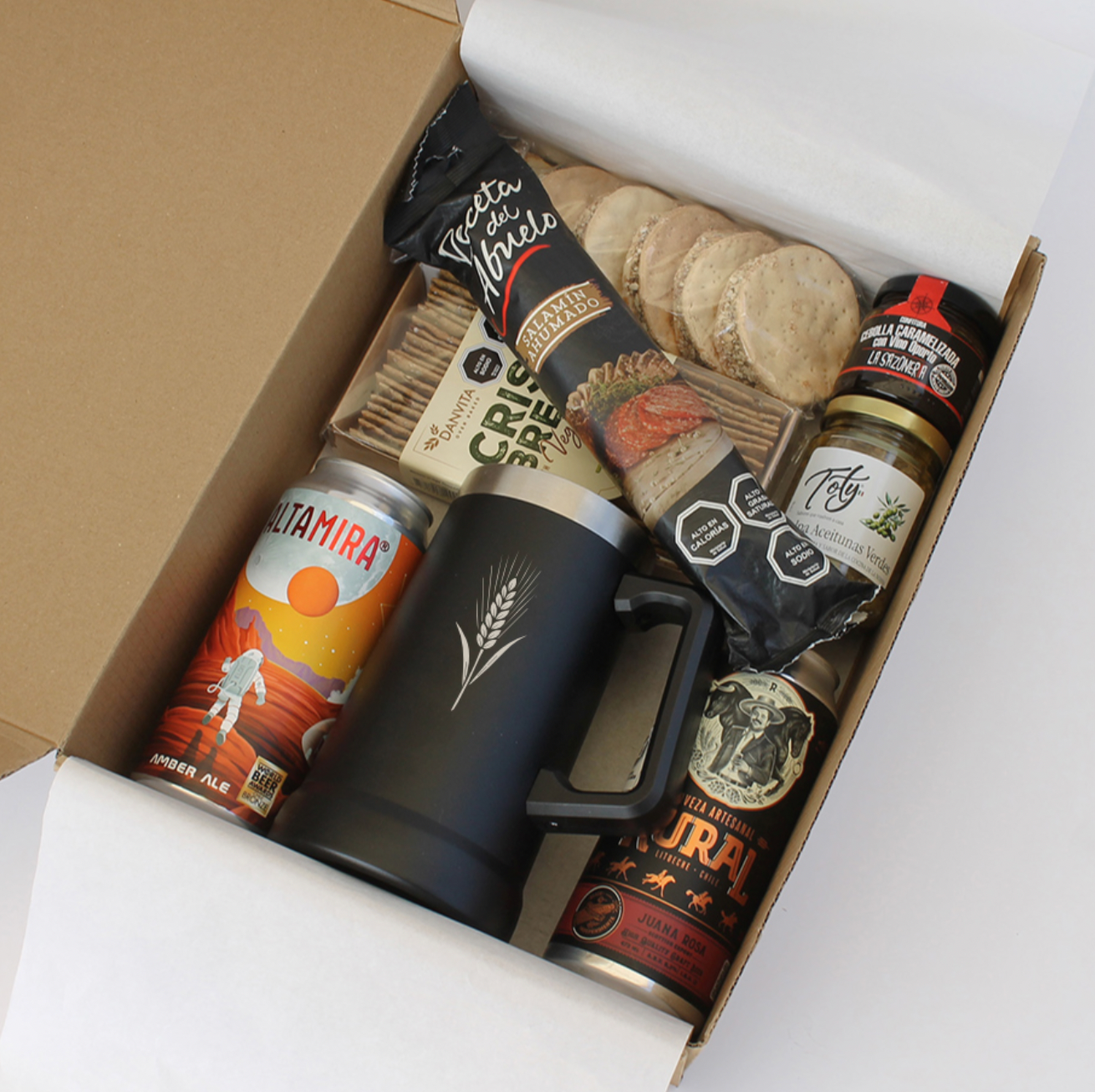 Exclusiva caja cervecera con jarro térmico, cervezas artesanales, salame, snacks gourmet y productos chilenos. Ideal para regalos corporativos premium.
