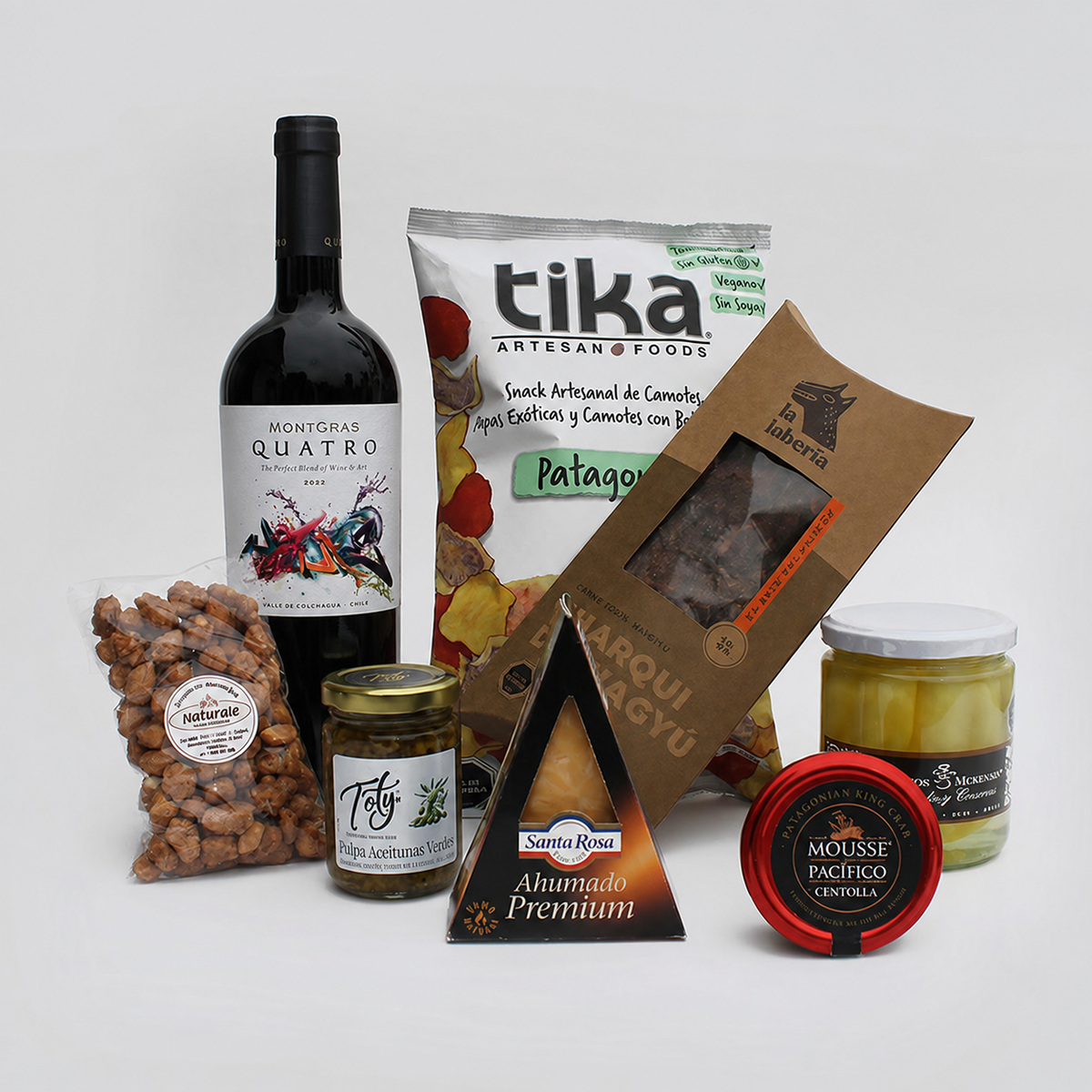 Exclusiva caja gourmet con vino Quatro Montgras (ensamblaje), papayas, queso ahumado, charqui de Wagyu, mousse de centolla y productos artesanales. Un regalo corporativo que recorre los sabores de Chile.