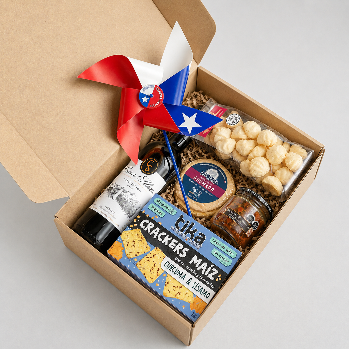 Caja gourmet con vino Casa Silva, queso ahumado, tapenade, crackers artesanales, bolsa merengue y remolino tricolor. Un regalo corporativo que celebra nuestras tradiciones y sabores.