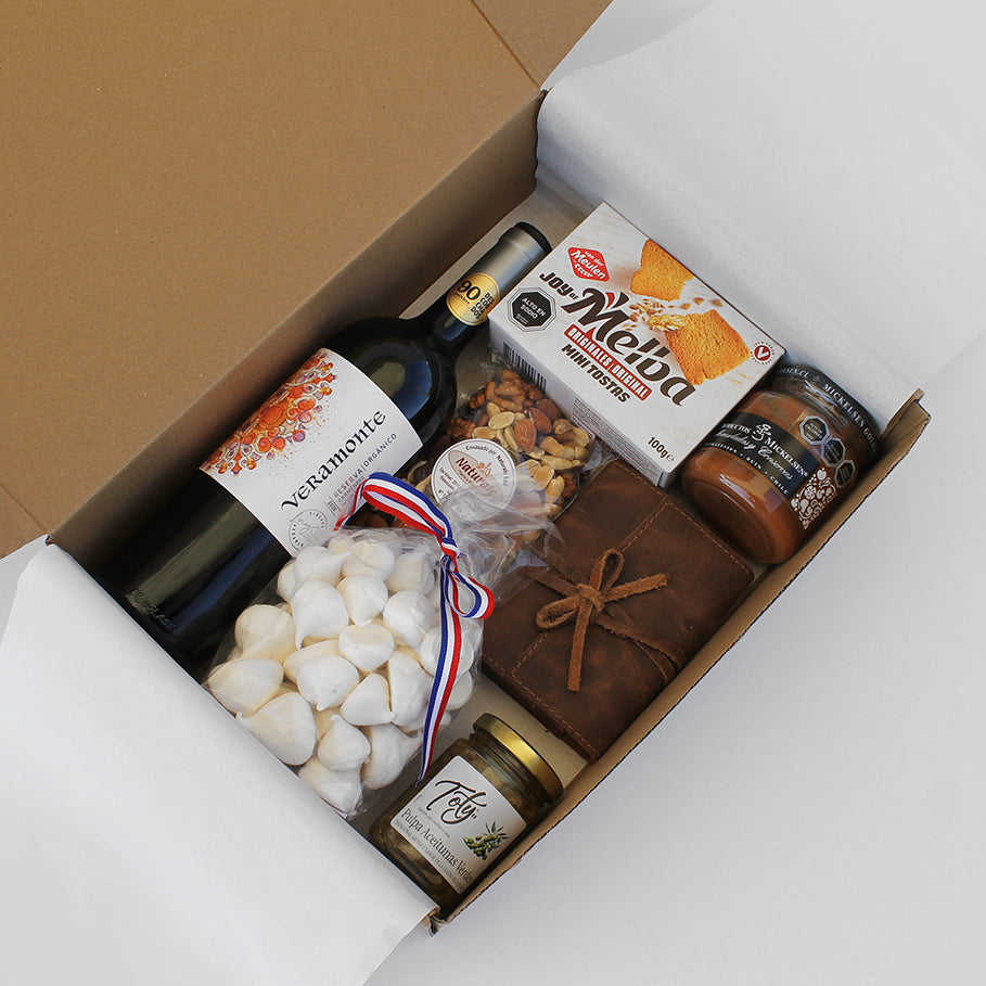 Caja gourmet con vino Veramonte, juego de naipes en estuche de cuero, dulces, frutos secos y productos gourmet. Un regalo corporativo ideal para compartir y disfrutar momentos memorables.