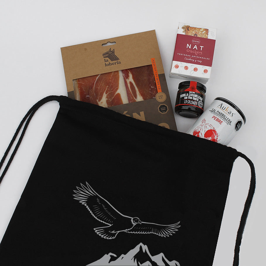Set gourmet con jamón serrano, confitura, crackers artesanales y sal parrillera de Atacama. En morral de algodón con logo corporativo.