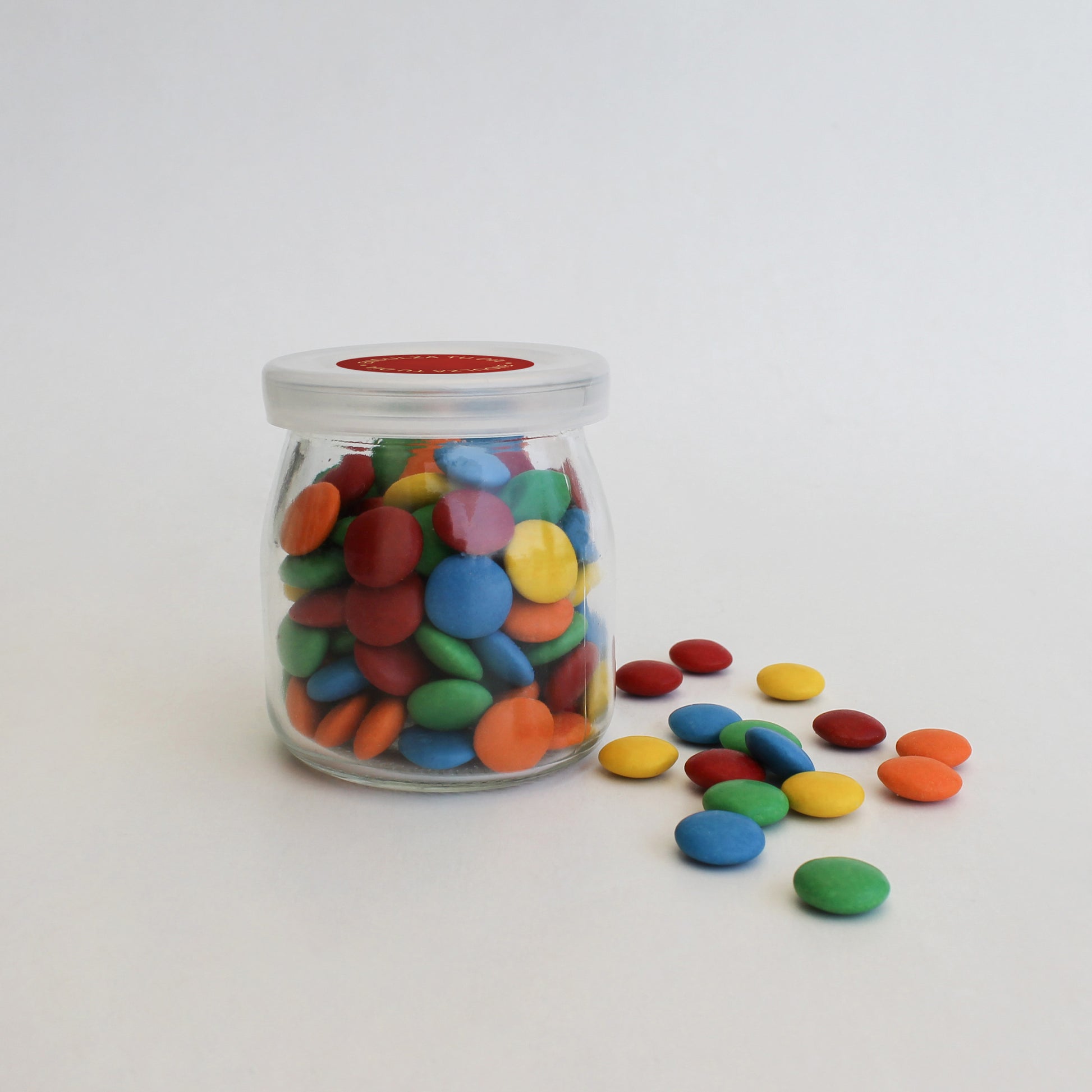 Frasco de vidrio reutilizable con chocolates Chubi y sticker personalizado. Detalle corporativo dulce y memorable.