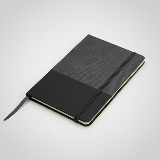 Libreta con tapa de cartón recubierta en poliuretano bicolor, 80 hojas rayadas, cierre elástico y cinta señaladora. Personalizable con logo corporativo.