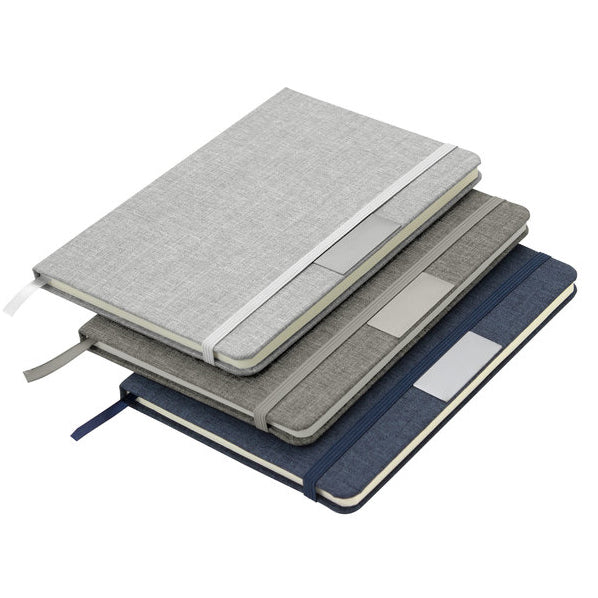 Libreta con tapa de cartón de 300 g, 80 hojas rayadas, banda elástica y placa metálica para grabado de logo. Disponible en varios colores.