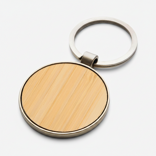 Llavero circular resistente de aleación de zinc con acabado brillante. Panel de bambú ideal para grabado o impresión de logo. Calidad premium para regalar.
