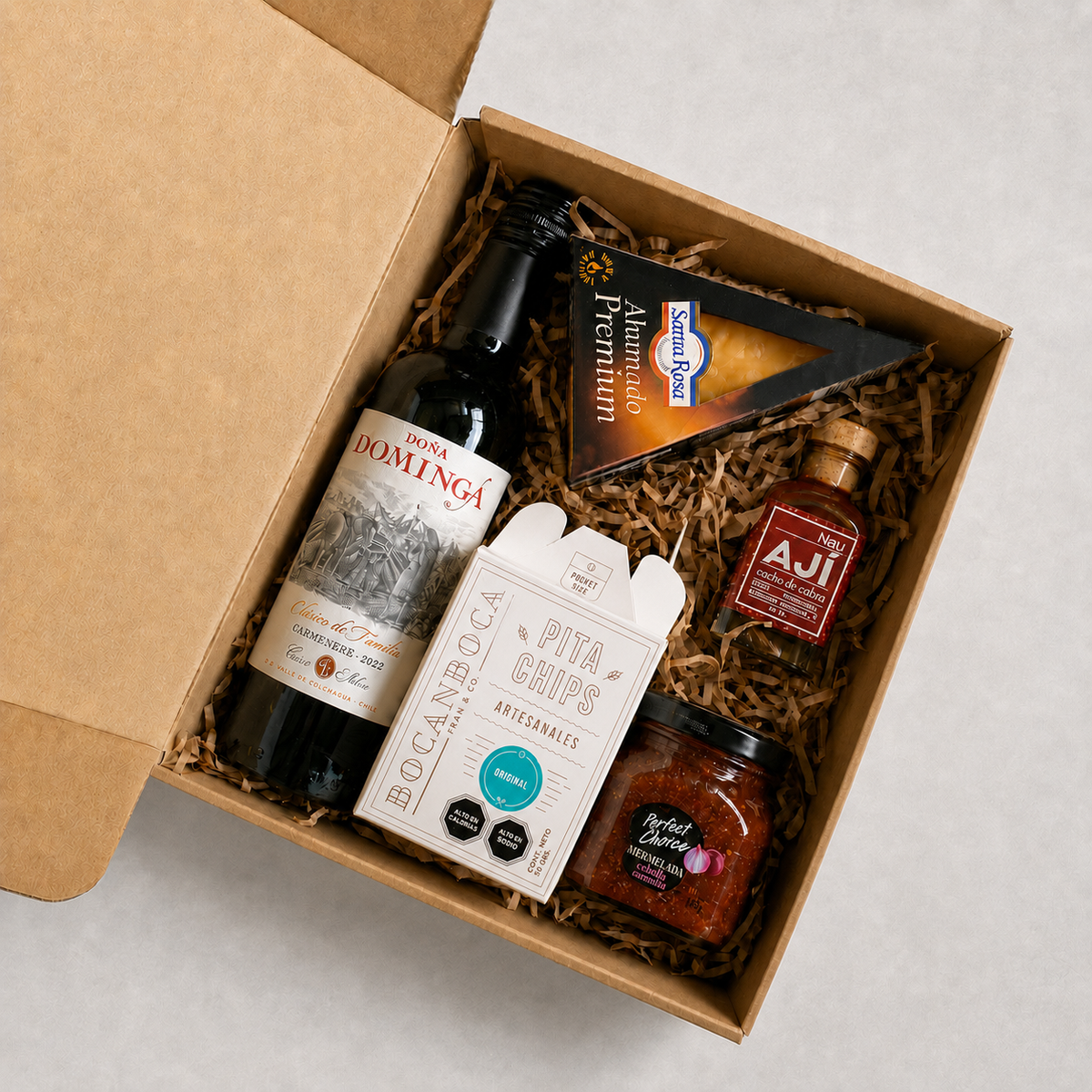 Mini caja gourmet con vino, queso ahumado, mermelada cebolla morada, ají artesanal y pita chips. Un regalo corporativo lleno de sabor, ideal para celebrar y compartir.