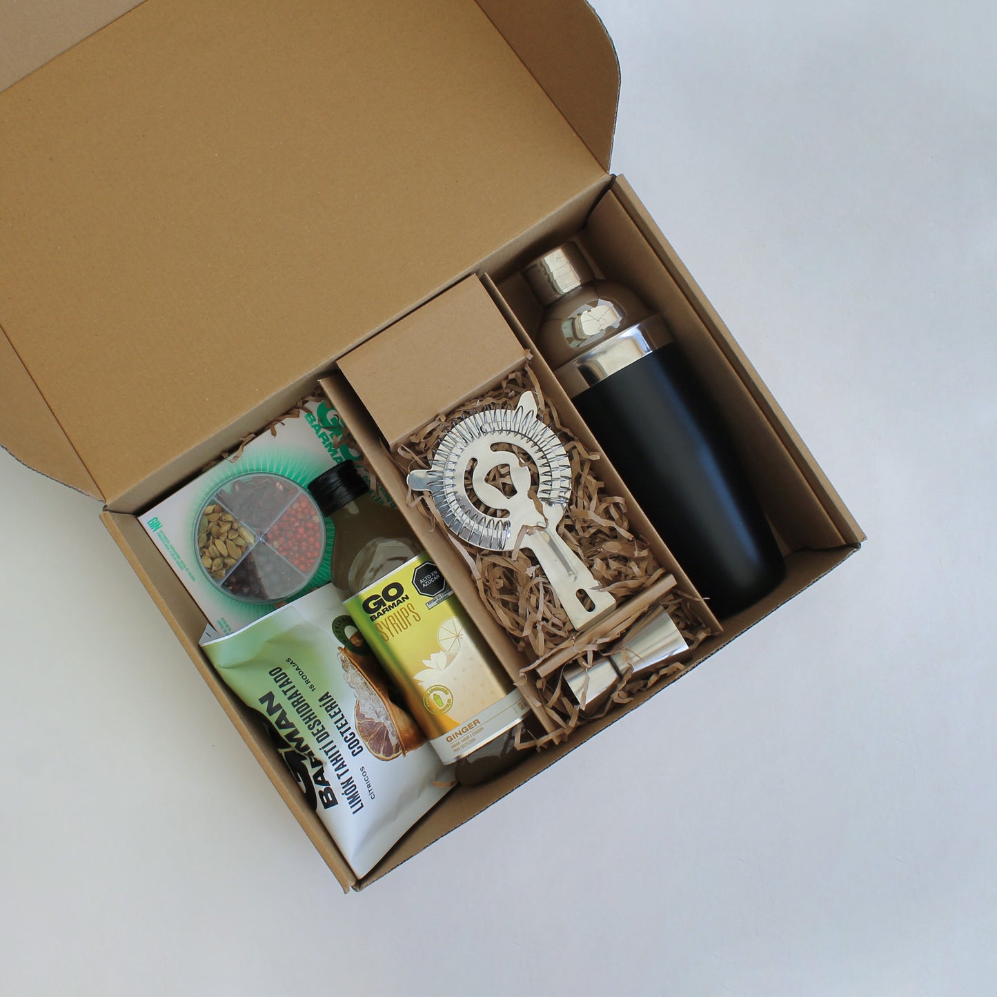 Regalo corporativo que contiene una coctelera 600ml, vaso mezclador, jigger, colador, botánicos, syrup y deshidratados Go Barman. Logo grabado opcional.