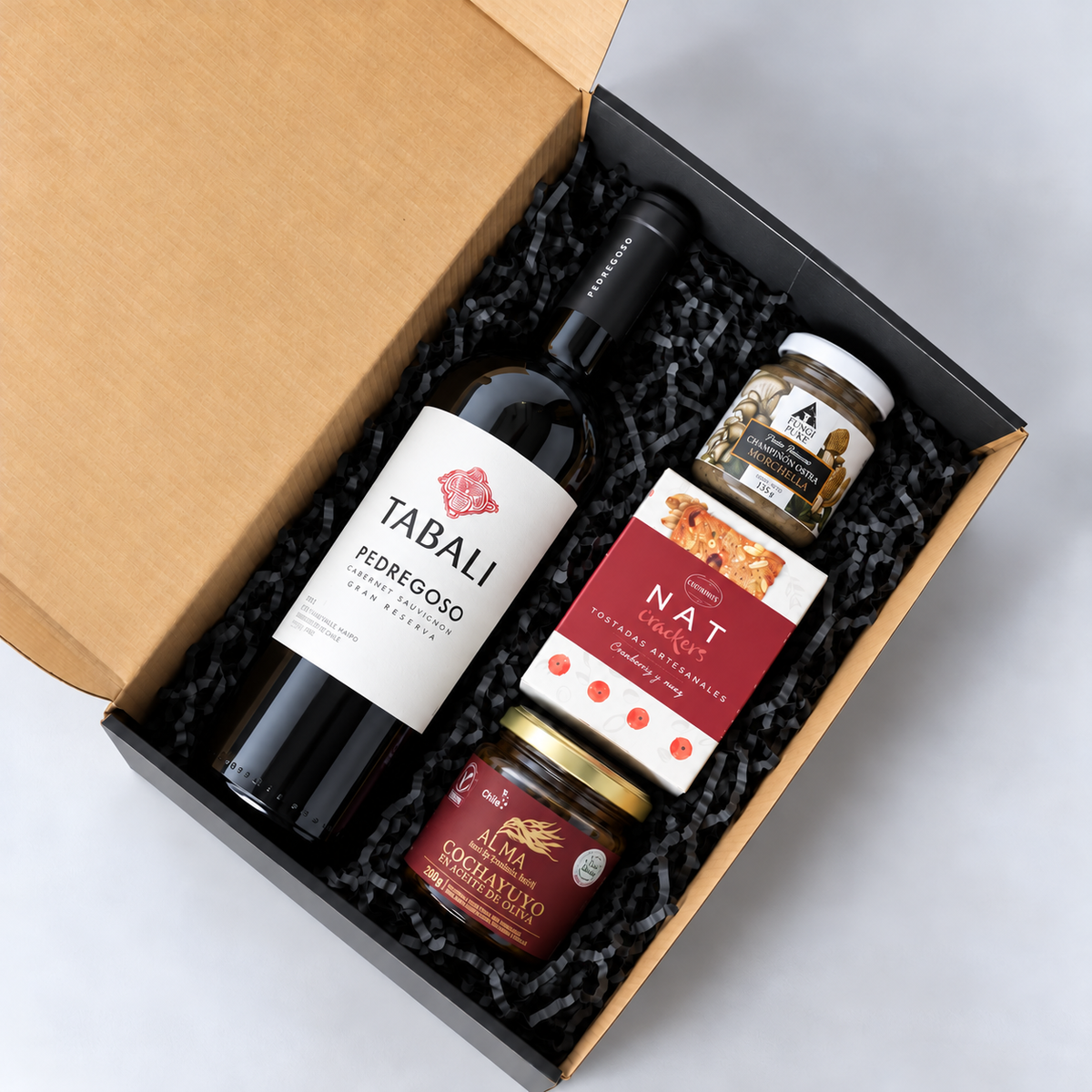 Caja con vino Tabalí Gran Reserva 750 ml, champiñones ostra a la morchella, Nat Crackers  y cochayuyo Alma en aceite de oliva. Con tarjeta de saludo alusivo a la fecha a celebrar. Cotiza con nosotros.