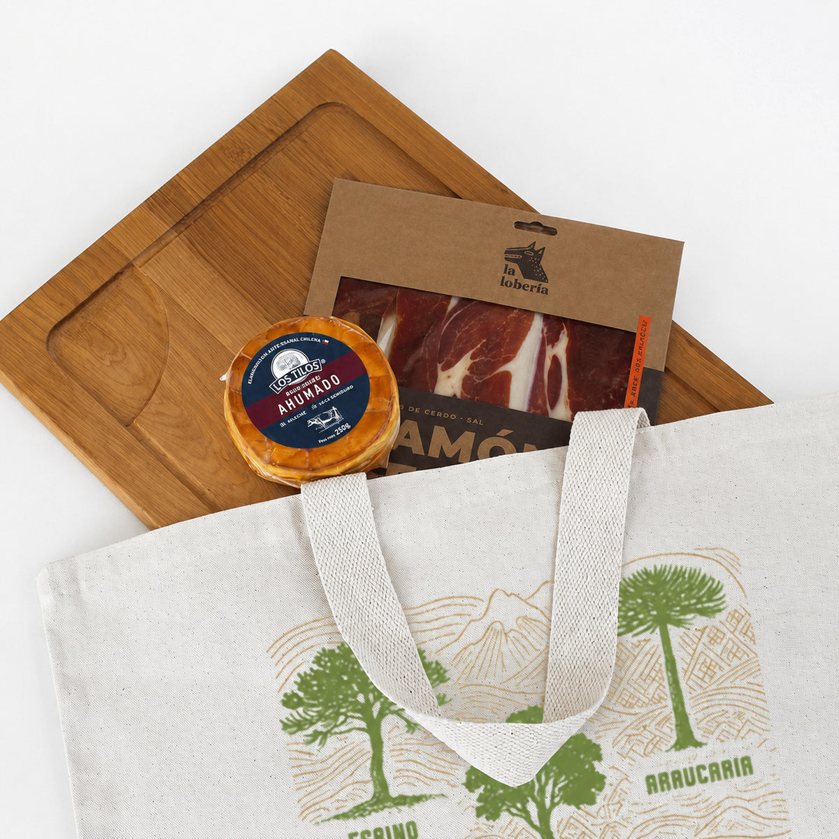 Kit Parrillero Premium: Tabla de lenga (34x48cm), selección gourmet y bolso de algodón natural con diseño nativo. La solución perfecta para regalos corporativos en el Día del Trabajador. ¡Cotiza!